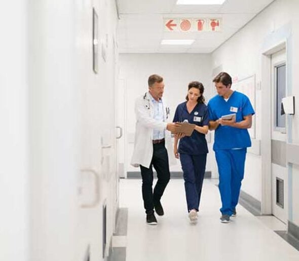 Medical staff in surgical attire, including masks and caps, standing and working together in a clinical setting